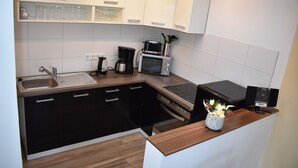 Et moderne køkken med vask, komfur, mikroovn og kaffemaskine.