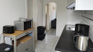 Eine kleine Küche mit einer Mikrowelle, einem Toaster, einem Wasserkocher und einer Wanduhr.