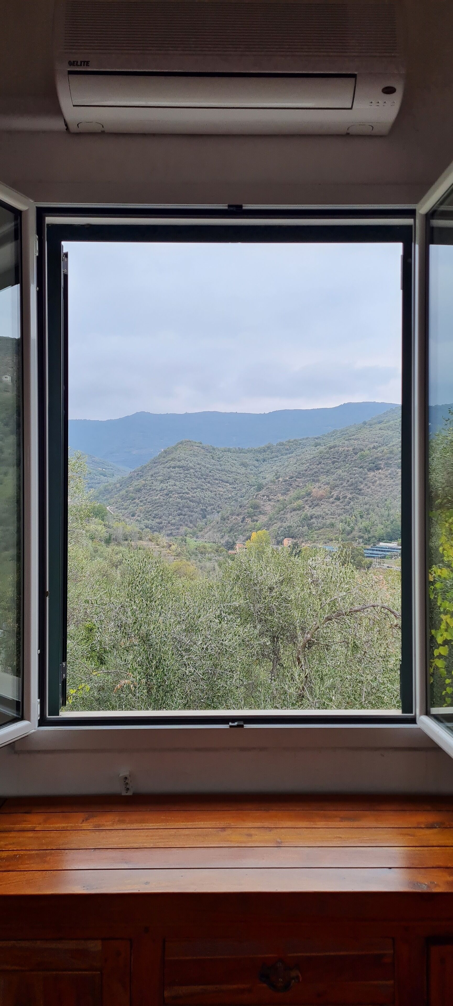 Ein Zimmer mit großem Fenster und Blick auf eine gebirgige Landschaft.