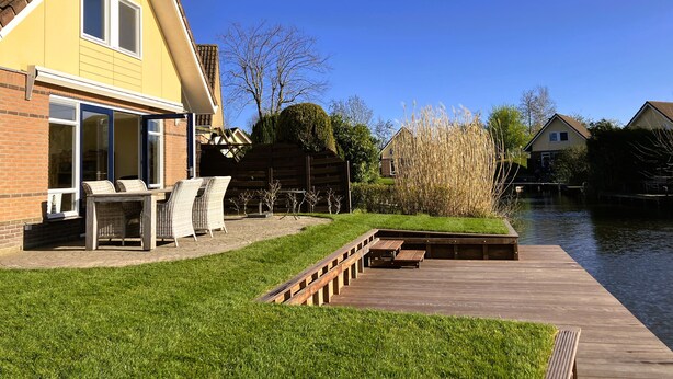 Una casa con patio, terrazza in legno e vista sul fiume.