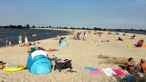 Una spiaggia con tende, persone e cielo sereno.