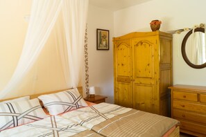 Une chambre à coucher avec un lit, une armoire en bois, une table de chevet, une lampe et un miroir.
