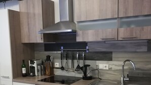 A modern kitchen with wooden cabinets, a stainless steel range hood, a built-in oven, a sink, and various kitchen utensils. - Apartment Auer family  (Tulfes)