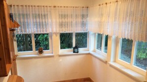 Una habitación con un ventanal grande, una mesita y un banco.