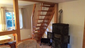 Una sala de estar acogedora con una escalera de madera, una chimenea y dos sillones.