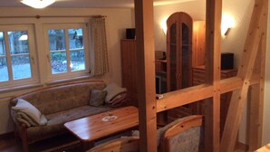 Una habitación acogedora con ventana de madera, un sofá, una mesita y una silla.