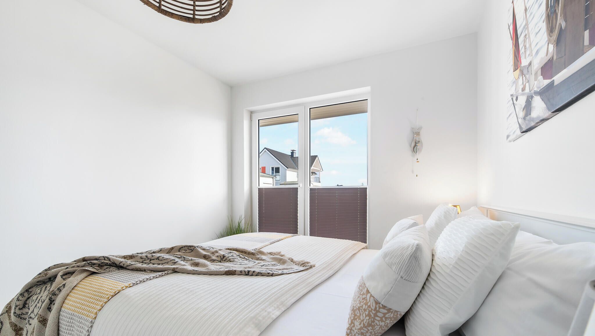 A bedroom with a bed, a window, and a view of houses.