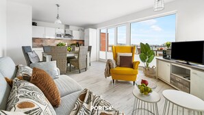 Una sala moderna con sofá, sillones, comedor y cocina.