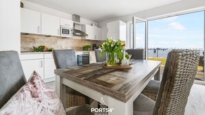 Una cocina moderna con armarios blancos, encimera de madera y vistas a la ciudad a través de amplios ventanales.