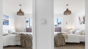 Un dormitorio moderno con una cama, una lámpara colgante y una ventana con vistas a edificios.