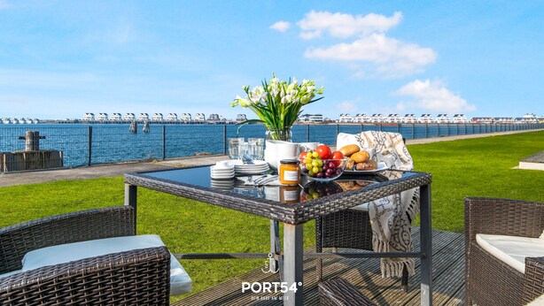 Un comedor con una mesa dispuesta para el desayuno, con vista a un muelle frente al agua.
