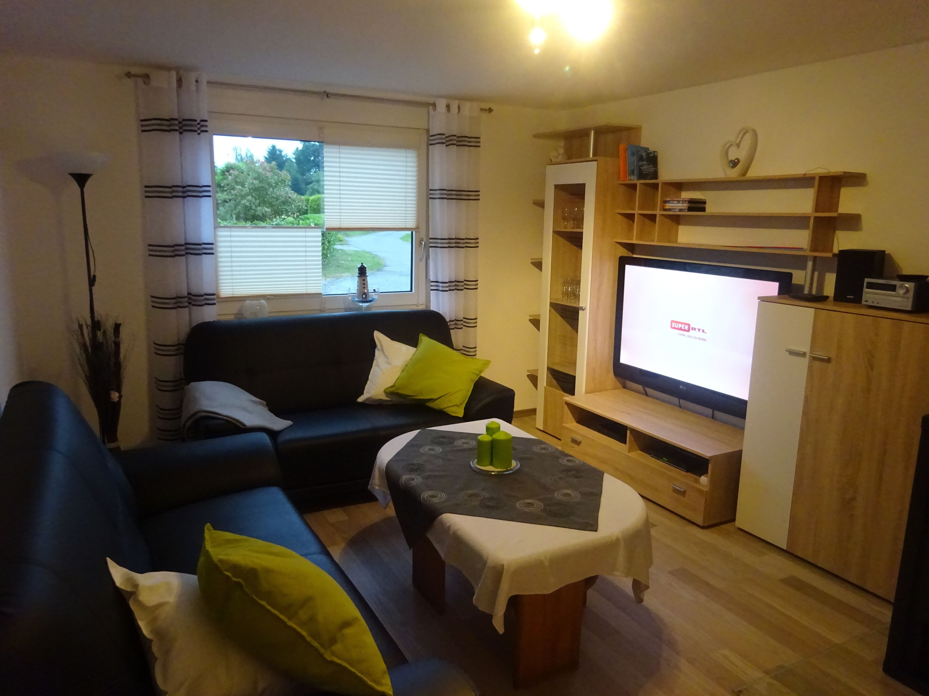 A living room with a sofa, a table, a TV, and a cabinet.