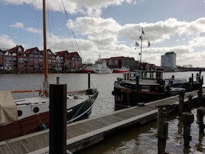 A dock with boats, a wooden pier, and buildings with red roofs in the background.