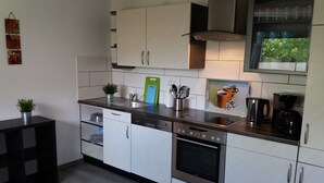 A modern kitchen with white cabinets, stainless steel appliances, a dishwasher, and a coffee maker.