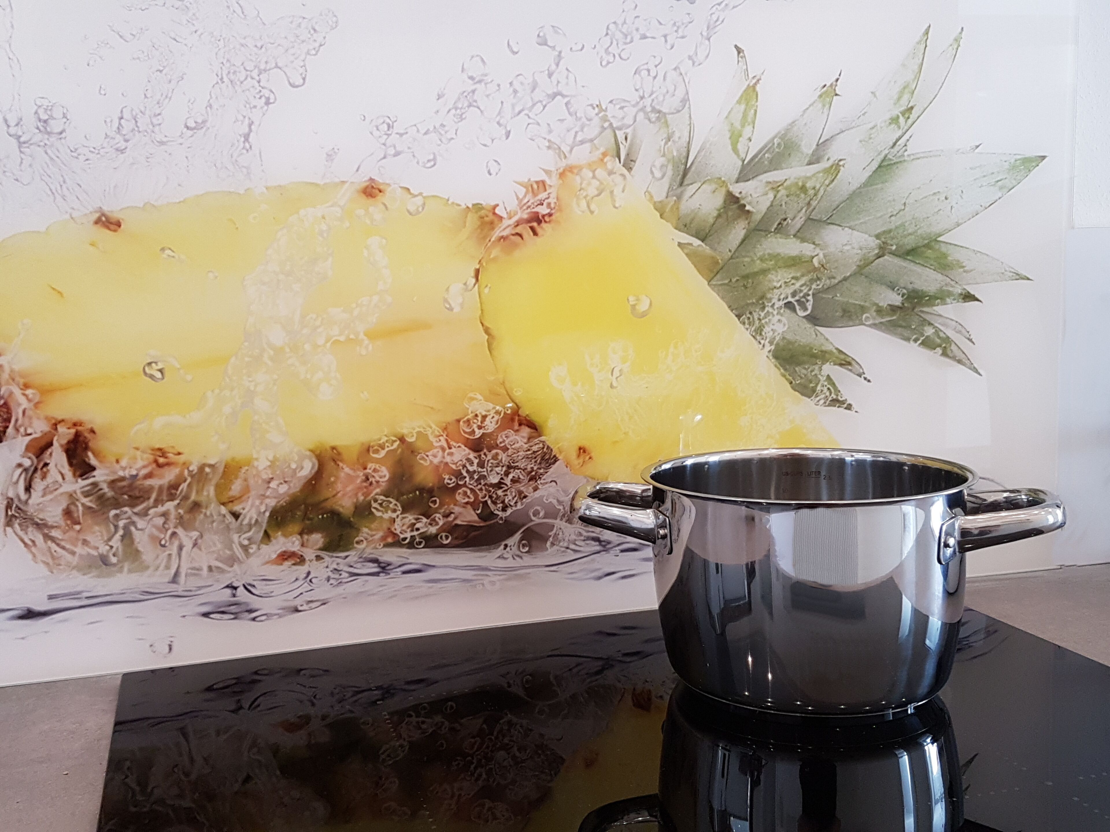 A kitchen counter with a steaming pot and a pineapple.