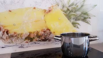 A kitchen counter with a steaming pot and a pineapple.