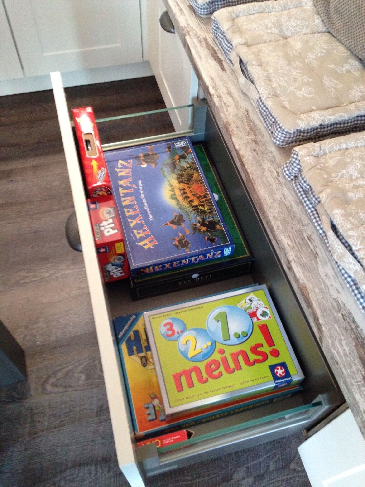 Een lade met gezelschapsspellen, waaronder 'The Xentanz' en '2.1 Meins!'