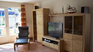Un saló amb televisió, un moble de fusta i una cadira.