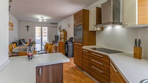 A modern kitchen with wooden cabinets, a built-in oven, and a stainless steel range hood.