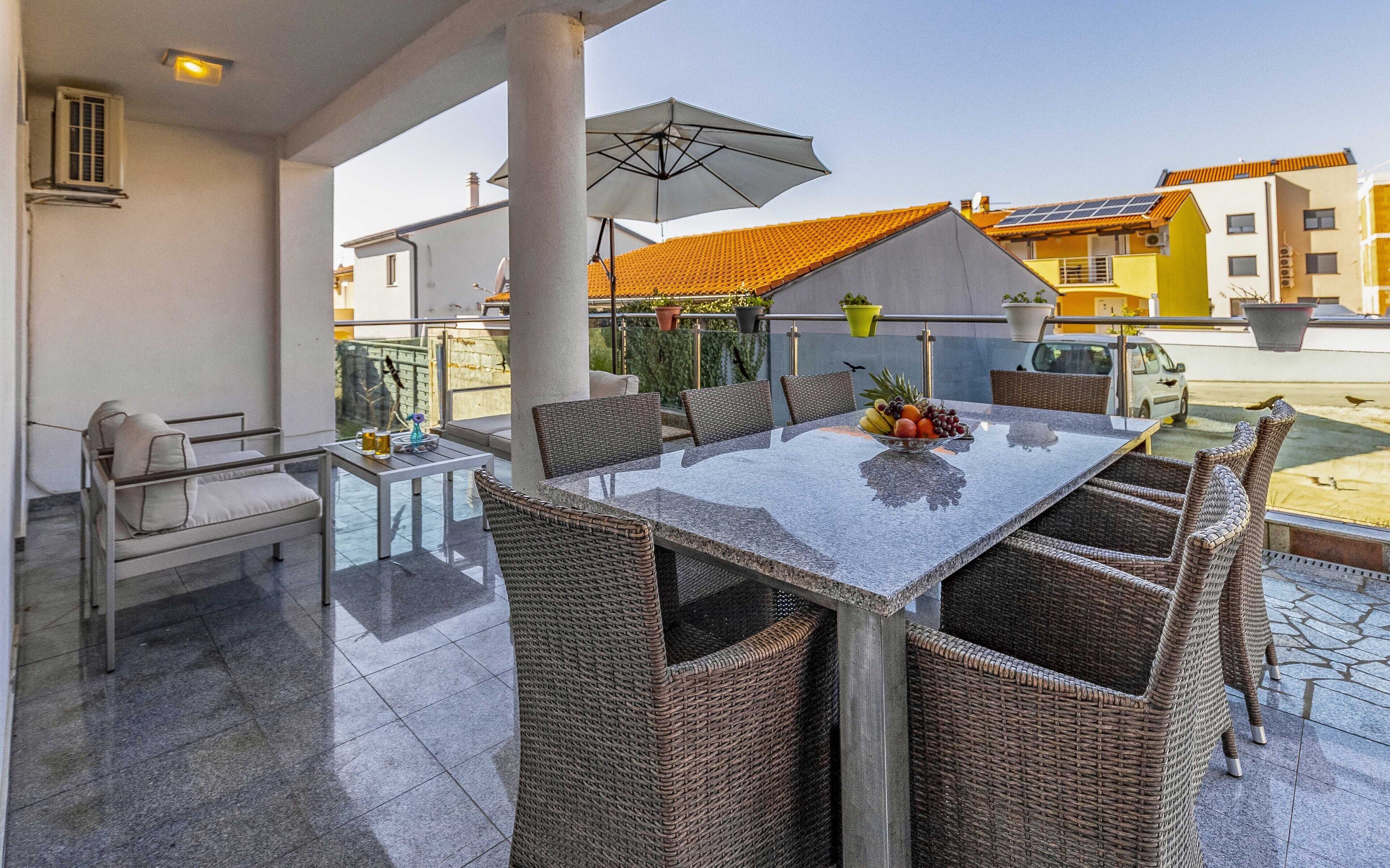 A dining area with a table, chairs, and an umbrella.