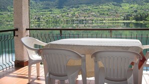 Eine Terrasse mit Tisch und Stühlen mit Blick auf einen See und ein Dorf.
