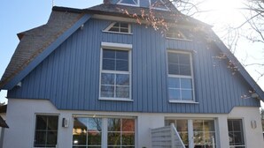 A two-story house with a gabled roof, large windows, and a visible staircase leading to the entrance. - BEAUTIFULLY FURNISHED HOLIDAY HOUSE FOR 4 PEOPLE WITH SEPERATE SAUNA HOUSE (Zingst)