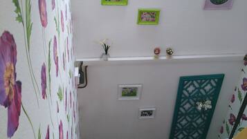 A staircase with floral wallpaper, a skylight, and several framed pictures on the walls.