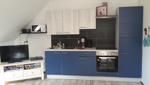 Una cocina compacta con armarios azules, microondas, cafetera y horno integrado.