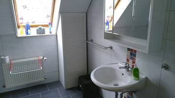 Un bagno con finestra, termosifone, lavandino e specchio.