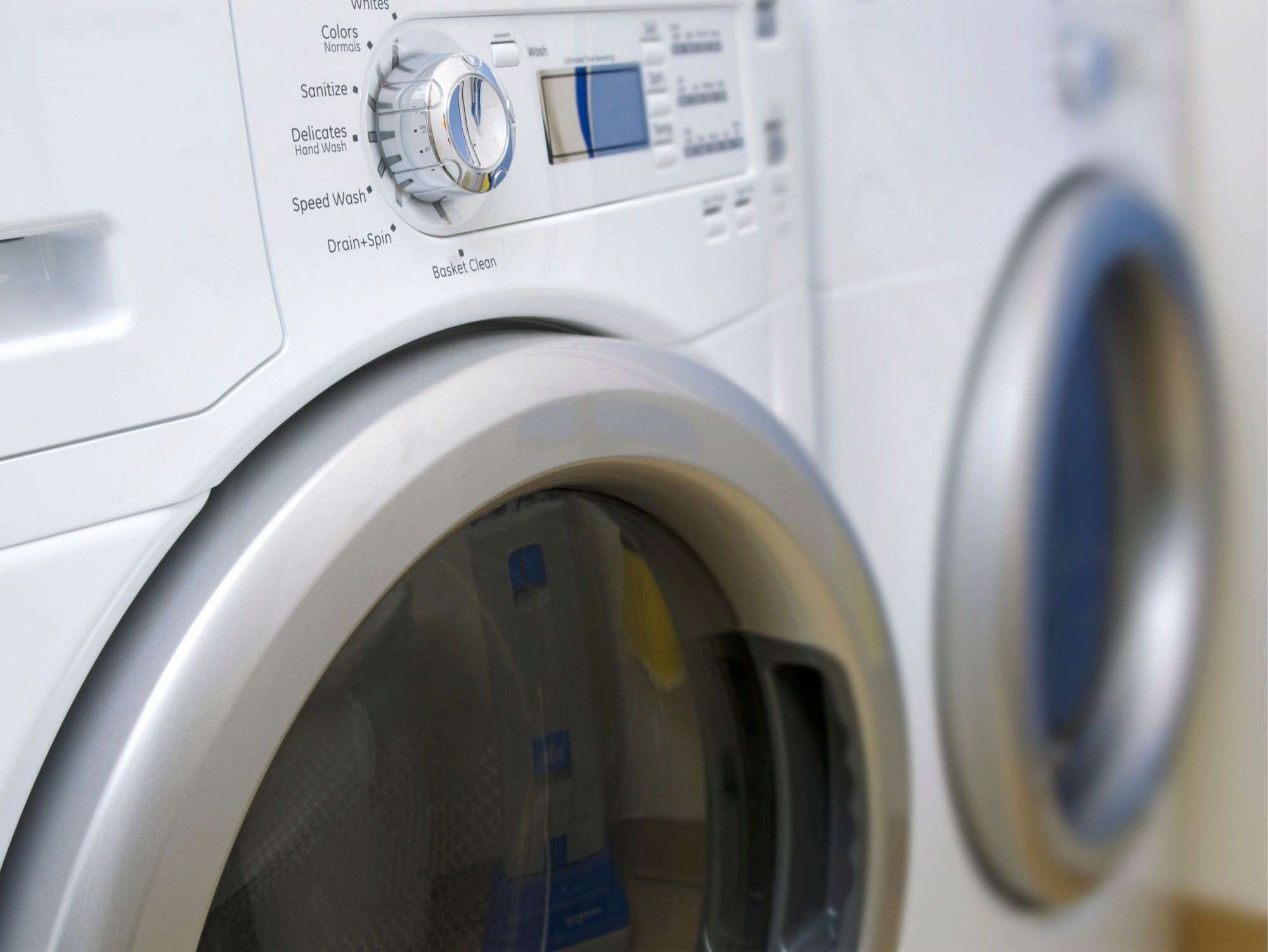 A front view of a front-loading washing machine with a control panel displaying various wash settings.