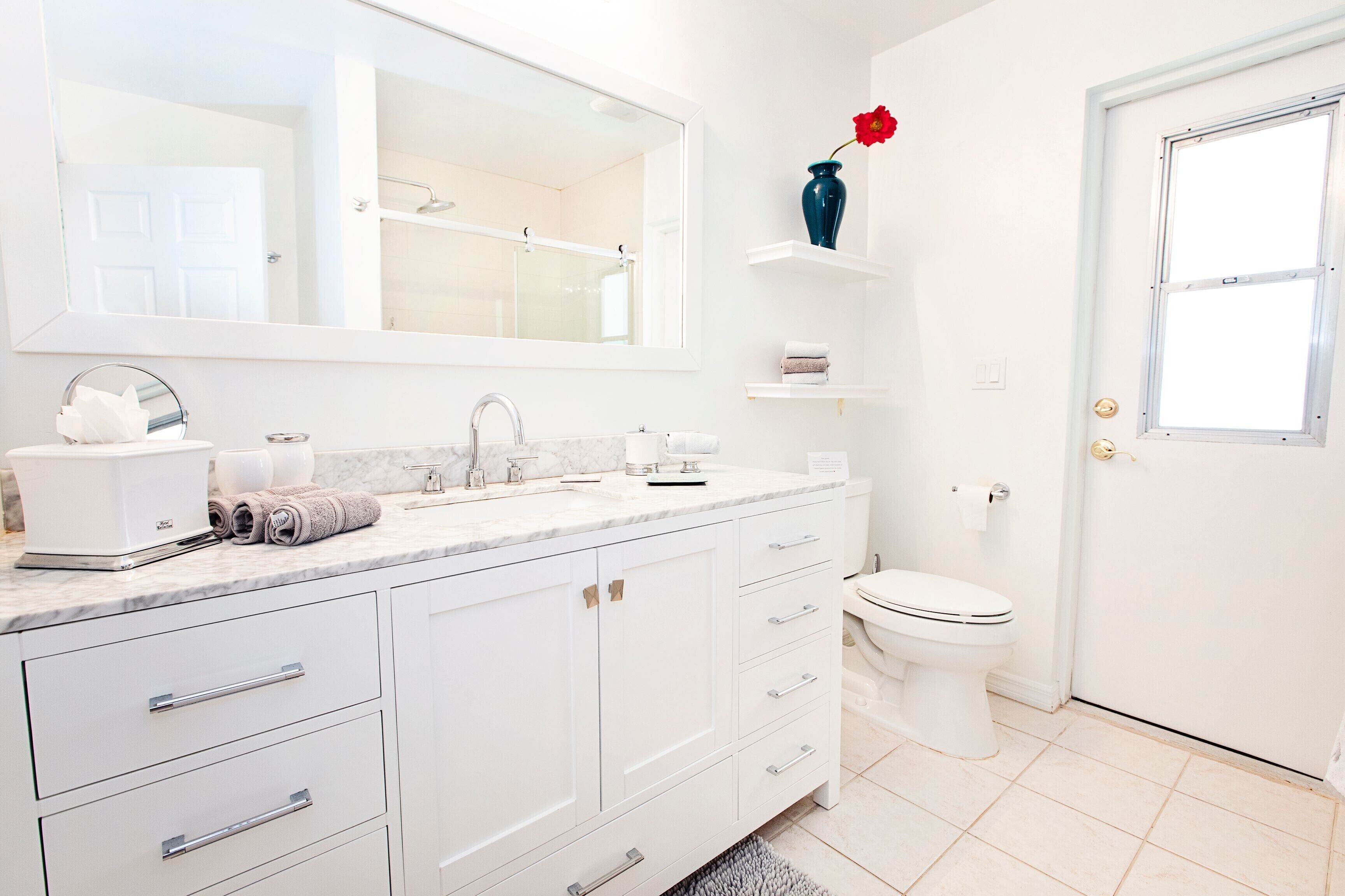 Une salle de bain moderne avec un meuble-lavabo blanc, un grand miroir, des toilettes et un espace douche.