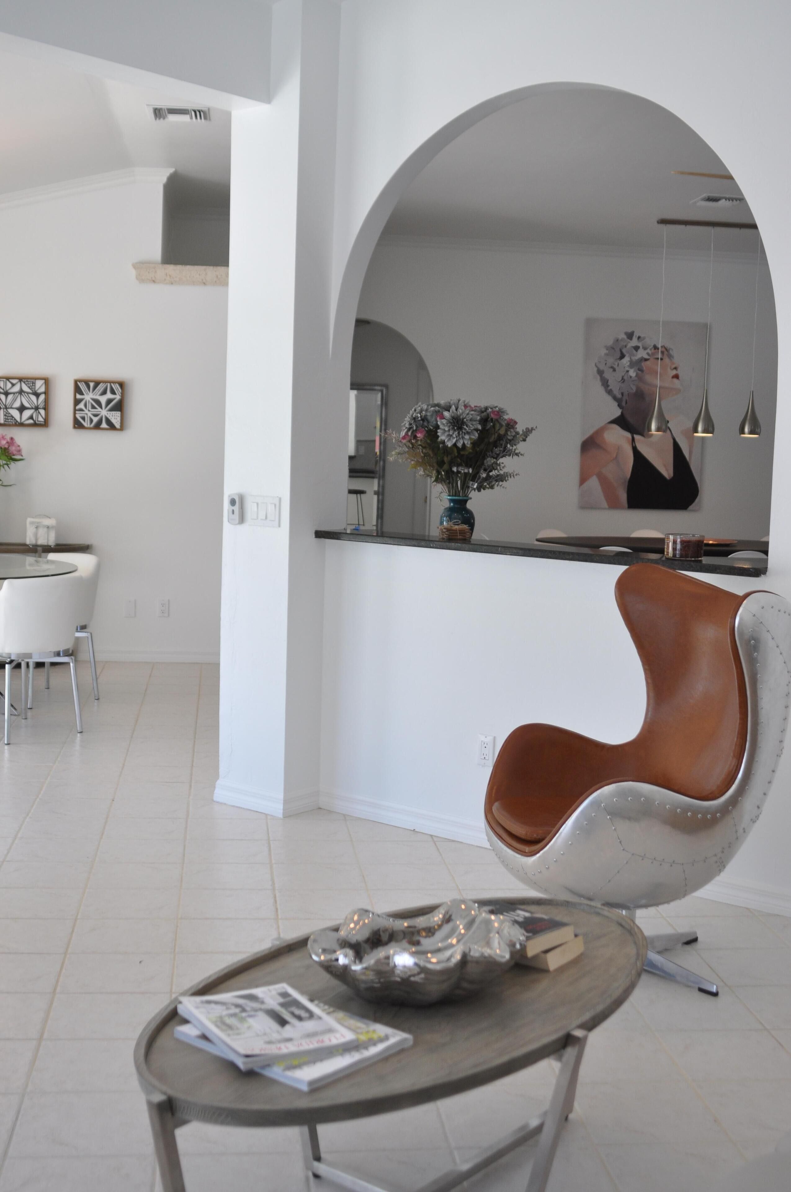 A modern kitchen with white cabinetry, a round dining table, and a unique curved chair.