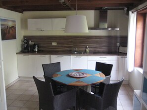 Un coin repas comprenant une table ronde, quatre chaises et un luminaire suspendu.