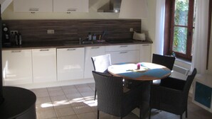A kitchen with white cabinets, a wooden countertop, and a dining area with wicker chairs.