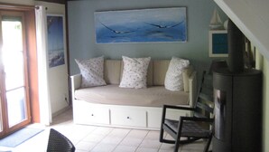 A cozy room with a sofa bed, a chair, a television, and a painting on the wall.