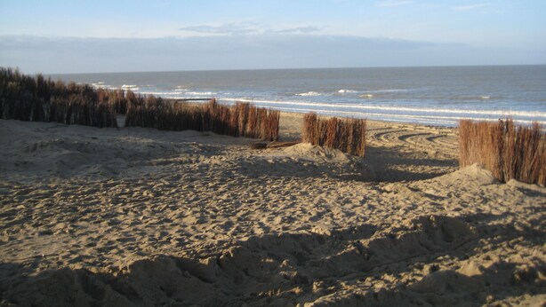 A sandy beach with waves and a clear sky.