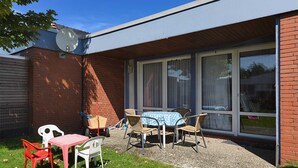 Een terras met een tafel en stoelen, een schotelantenne en een bakstenen muur.