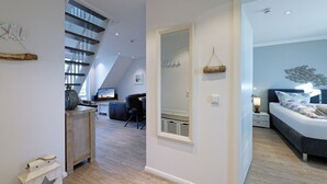 Ein modernes Interieur mit einer Treppe, einem Wohnbereich mit Fernseher und einem Schlafzimmer mit Bett und Nachttisch.