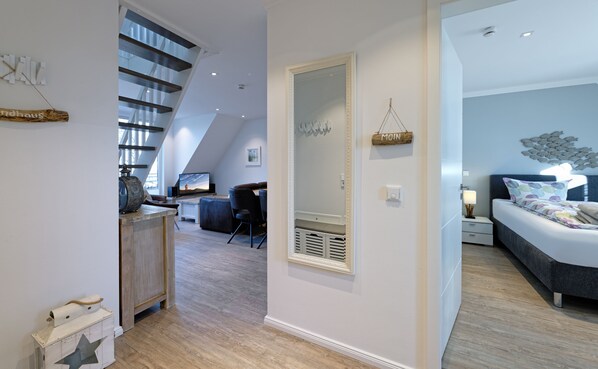 Ein modernes Interieur mit einer Treppe, einem Wohnbereich mit Fernseher und einem Schlafzimmer mit Bett und Nachttisch.