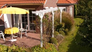 A patio with a table and chairs, a yellow umbrella, and a white pergola. - Sunny spacious. DHH, 3 bedrooms, 6 pers., NR, WLan, close to the beach, washer + dryer (Niedersachsen)