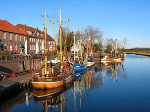 A calm waterway with several boats docked, a bridge, and buildings in the background.