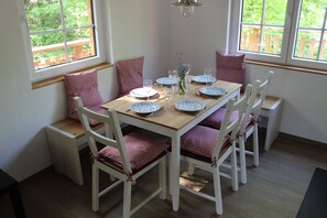 A dining table set for four with checkered cushions, white chairs, and a vase with flowers. - Comfortable holiday home with charm, located directly between lake and forest (Möhnesee)