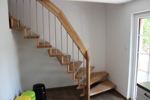 A wooden staircase with metal railings in a room with white walls and a window. - Comfortable holiday home with charm, located directly between lake and forest (Möhnesee)
