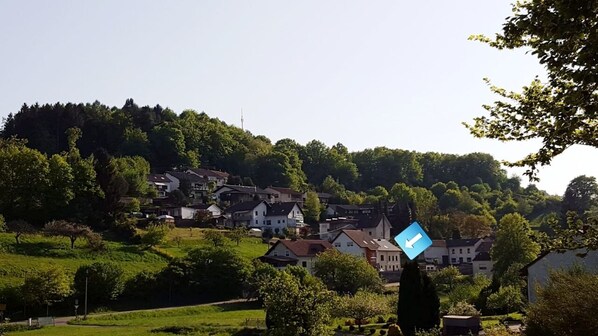 A residential area with houses on a hillside, a clear sky, and a directional sign.