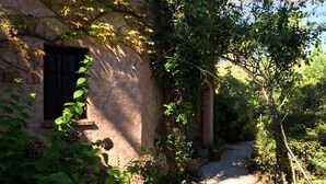 Un edificio rústico de piedra con una ventana y un camino de grava que lo conduce.