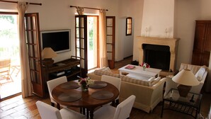 Una sala de estar acogedora con chimenea, televisor y comedor con mesa y sillas.