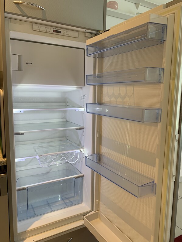 Un refrigerador abierto con varios estantes transparentes y un panel de control.