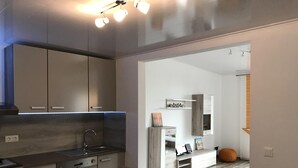 Cozinha moderna com armários embutidos, mesa de jantar de madeira e vista para a sala adjacente.