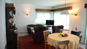 A cozy living room with a TV, comfortable seating, a dining table with fruit, and a bookshelf. - Beautiful house with a fascinating sea view - close to the beach (Tacoronte)