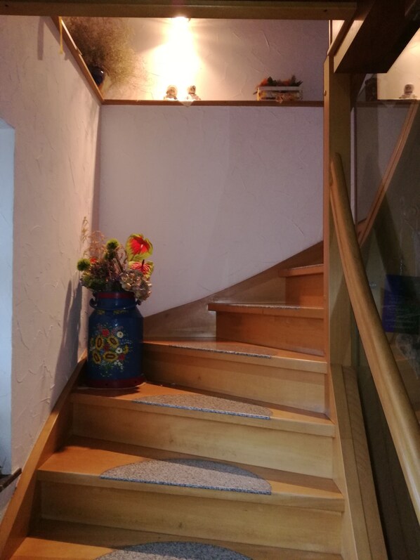 A wooden staircase with a blue vase of flowers on the left. - Luxurious, spacious **** apartment on a farm - family friendly (Tann (Rhön))